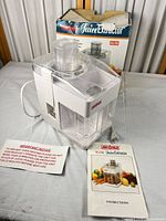Juicer with manual and power cord displayed on table