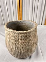 Front view of beige ceramic planter showing woven texture and shape