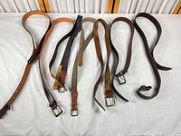 Seven belts laid out showing full length and buckles