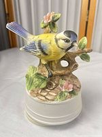 Front view of porcelain music box showing bird, flowers and base