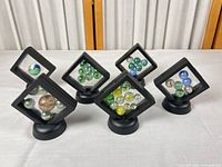 Group of five display frames holding assorted marbles