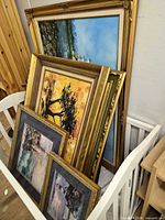 Group of framed artworks stacked in crib