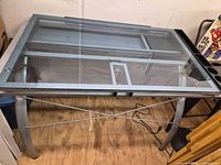 Full view of glass drafting desk, glass top, metal frame, cross-brace