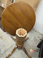Round tabletop leaning against wall showing wood grain