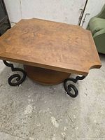 Full view showing square burl veneer top, canted corners, black scroll legs, round shelf