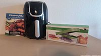 Black PowerXL air fryer centered, PowerXL booklet at left, boxed Progressive Prepworks chopper at right