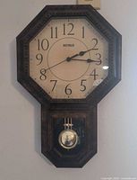 Front view of Benrus octagonal wall clock showing dial, hands, brand name, pendulum compartment
