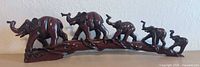 Side view of carved wood elephant sculpture showing six elephants