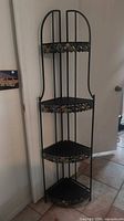 Full view of black metal corner shelf showing three shelves and polished stone trim