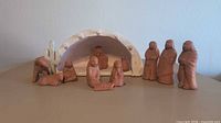 Full view of all ten clay nativity pieces arranged together.