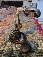 Front view showing gear base, elbow arm, chrome lamp head, bulb, power cord, switch