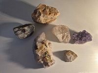 Six mineral specimens arranged on white surface
