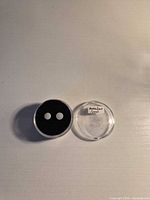 Two loose round opal cabochons in a display case next to clear lid
