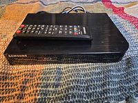 Front and top view of Blu-ray player with remote resting on unit
