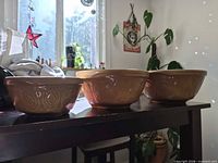 All three tan ceramic embossed mixing bowls on table, nested side by side