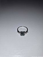 Front view of sterling silver ring showing rectangular green center stone and side stones