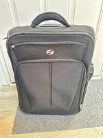 Front view showing American Tourister badge, front pockets and overall condition