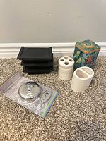 Group shot of all items: packaged clothesline, three black shelves, two ceramic organizers, decorative tin