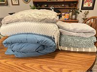 Stack showing blue comforter, two throw blankets, two bath mats
