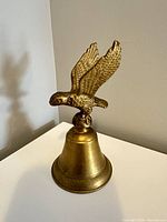 Front view of brass bell showing bird finial and full height