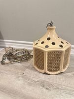 Full view of lamp showing ceramic body, rattan panels, and attached chain/cord