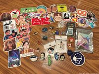 Overview of pins, stickers and packaged locket on wooden surface