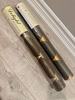 Two sealed rolls of Delight black and gold wallpaper lying on floor