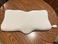 Top view of entire white contoured cervical pillow on table