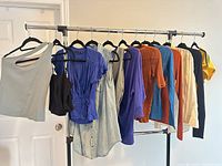 Full rack view showing twelve assorted tops on hangers