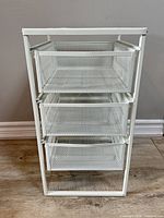 Front view showing three mesh drawers within white metal frame