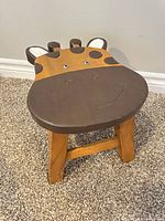 Front view of wooden giraffe stool showing carved seat design