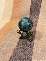 Marble sphere resting on ornate metal stand, frontal view