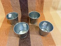 Top angled view of four silver galvanized pots upright on fabric background