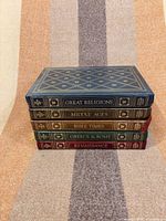 Stacked view of five gilt leather hardcovers showing top cover of Great Religions