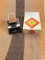 Camera partially unfolded beside original box