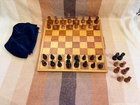 Overhead view showing folding wood board, full set of pieces, spare pieces, velvet pouch