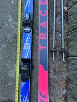 Top view of one ski showing bindings, measuring tape alongside, and poles