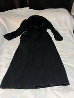Full view of black long coat laid flat showing overall length and design