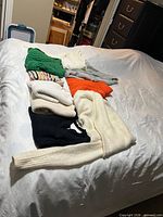 All eight sweaters laid out on bed