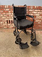 Front angled view of Drive Medical transport wheelchair showing seat, backrest and footrests