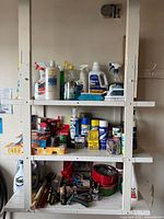 Full view of shelving with cleaners on top shelf, aerosol cans on middle, tools on bottom