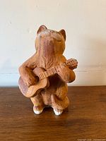 Full rear-angle view of cat statue showing overall form and guitar