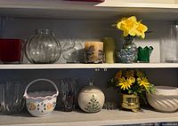 Shelves displaying assorted glass vases, ceramic basket, candleholder, artificial flowers, ornament, planter, bowl