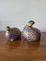 Front view of both multicolour quail figurines