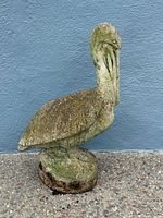 Front left view of entire pelican statue showing weathered concrete and base