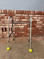 Front view of aluminum walker showing wheels and tennis ball glides