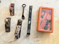Group shot of three block planes, crowbar, hex wrench, orange tool case