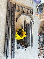 Disassembled steel uprights, crossmember, brace bars laid out on floor