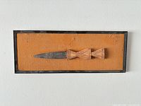 Front view of framed knife on orange backing
