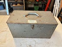 Top view of closed gray-green metal toolbox with handle and clasp